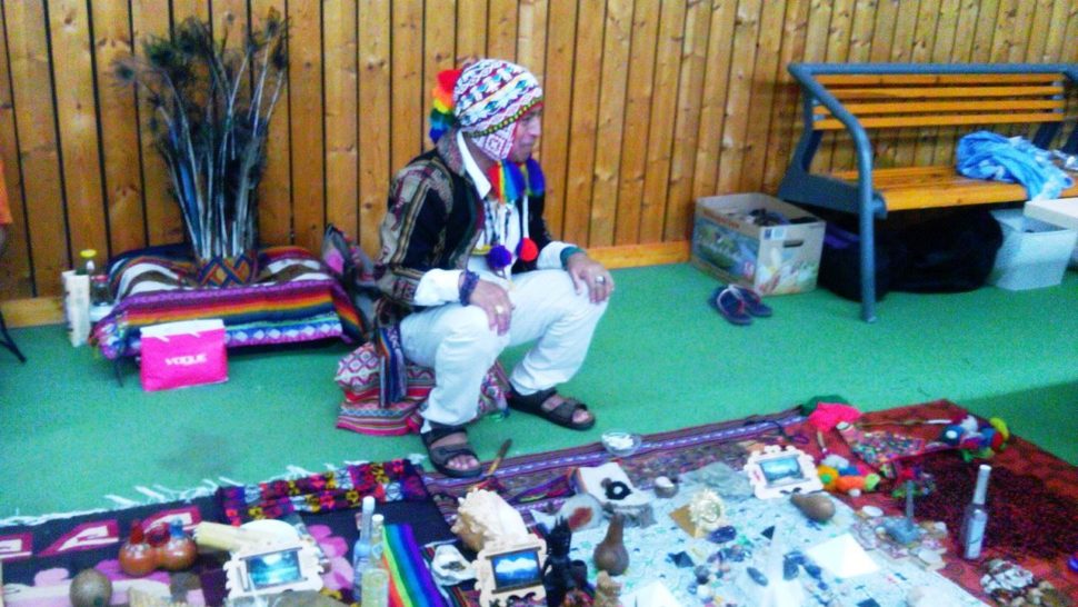 andský šaman Don Sergio před rituálem hojnosti, za ním čelenka s pavími pery